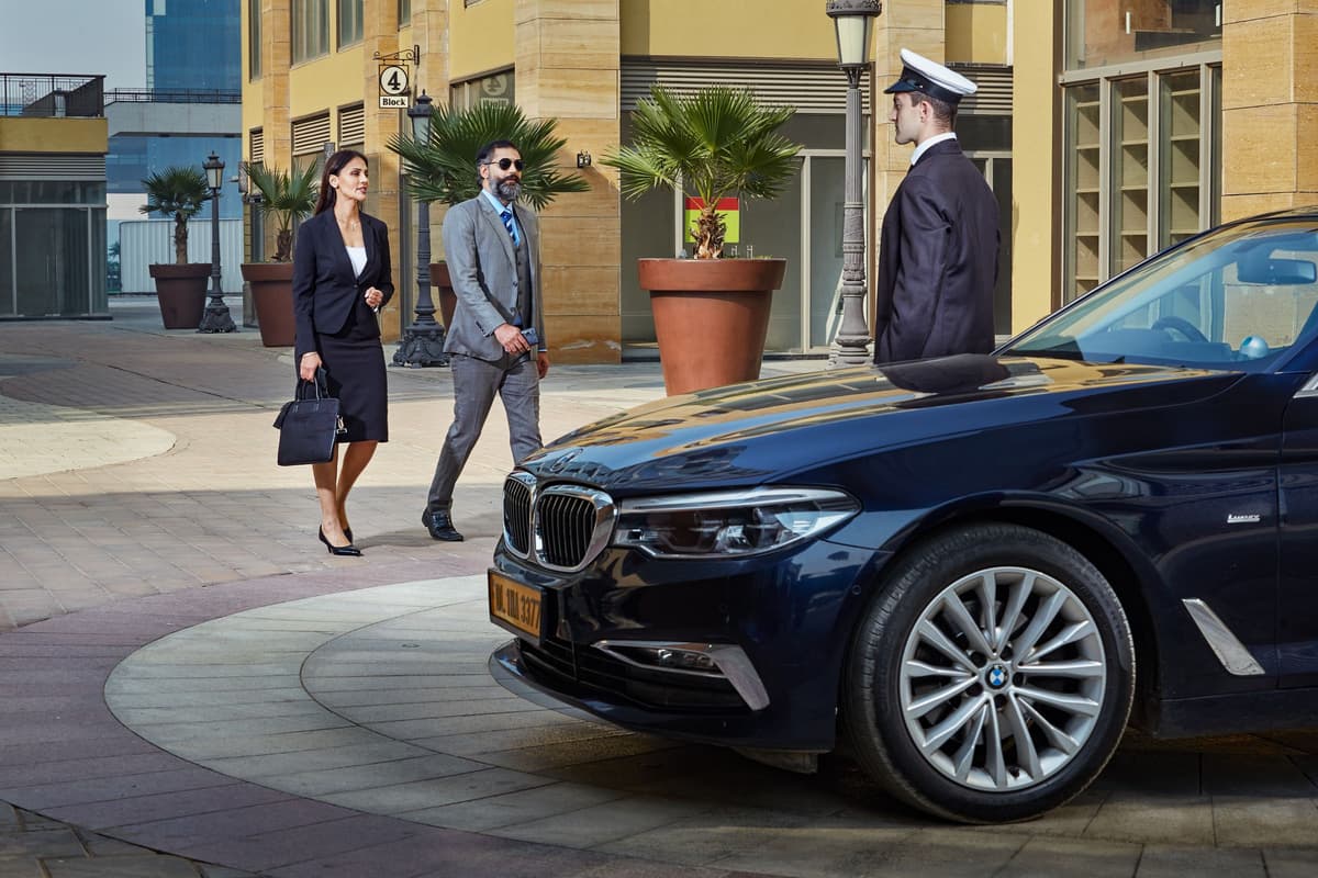Chauffeur holding the door of a black executive saloon for arriving passengers - Malta airport transfer